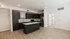 Modern apartment kitchen with sleek dark cabinetry, stainless steel appliances, and a stylish center island on elegant wood flooring.