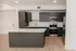 Modern kitchen with sleek grey cabinets, stainless steel appliances, and a stylish island on elegant wooden flooring.