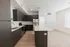 Sleek modern kitchen with dark cabinetry, stainless steel appliances, and a spacious island on hardwood floors.