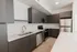 Modern kitchen with sleek dark cabinets, stainless steel appliances, and elegant white countertops.