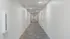 Modern, well-lit apartment corridor featuring smooth white walls and elegant carpet flooring.