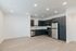 Modern kitchen with sleek dark cabinetry, stainless steel appliances, and spacious layout. Bright lighting enhances the contemporary feel of the open space.