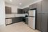 Modern kitchen with sleek gray cabinets, stainless steel appliances, and elegant light wood flooring.