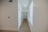 Bright modern hallway with elegant wood flooring, sleek white walls, and ample natural light through large blinds.