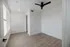 Bright and airy room with sleek wood flooring and a modern ceiling fan, perfect for a minimalist touch.