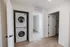 Modern apartment featuring a convenient in-unit stacked washer and dryer, adjacent to a spacious open closet and bright rooms.