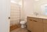 Modern bathroom featuring stylish wooden cabinetry, a sleek countertop, and a classic shower curtain for a cozy ambiance.