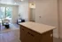 Bright and modern living space with a chic open layout, featuring sleek wood flooring, a cozy seating area, and large windows overlooking lush greenery.