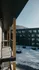 Charming apartment balcony overlooking a snowy courtyard with modern architecture and scenic mountain views.