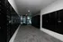 Modern mailroom with sleek black mailboxes and secure package lockers, leading to a bright entrance with glass doors.