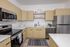 Sleek modern kitchen with stainless steel appliances, stylish light wood cabinets, and elegant countertops.