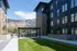 Modern apartment complex with sleek architecture, lush green courtyard, and stunning mountain views.
