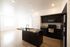Bright and modern kitchen with sleek black cabinets, spacious island, and natural wood flooring ideal for entertaining.