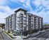 Modern apartment building with stylish balconies and large windows, set in an urban environment with scenic mountain views.
