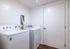 Contemporary laundry room with sleek white washer and dryer set, featuring elegant wood flooring and modern fixtures.