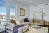 Bright and inviting living room with a cozy beige sectional, modern decor, and large windows offering a charming urban view.