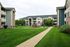 Charming apartment complex with manicured lawns, surrounded by modern three-story buildings and a vibrant playground, perfect for families.