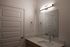 Modern bathroom with sleek vanity, illuminated mirror, and sophisticated fixtures.