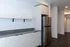 Modern kitchen with sleek cabinetry, stainless steel refrigerator, and open shelving, ideal for contemporary living.