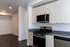 Modern kitchen with sleek white cabinets, stainless steel appliances, and elegant dark wood flooring, offering a spacious and functional cooking environment.