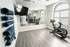 Modern fitness room with sleek exercise bike, mirrored wall, and neatly arranged yoga mats on wooden flooring.