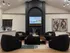 Chic and modern living room featuring sleek black armchairs, a stylish brick fireplace, and contemporary art, perfect for leisurely gatherings.