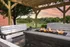 Inviting outdoor fire pit area with cozy seating under a wooden pergola, overlooking a serene lake and lush greenery at sunset.