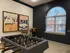 Chic recreation room with modern foosball table, cozy seating, and vintage car artwork under elegant arched window.