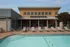 Inviting poolside view featuring modern lounge chairs and a stylish building with solar panels, perfect for relaxation and leisure.