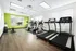Modern apartment fitness center with state-of-the-art treadmills, elliptical machines, and bright green accent wall.