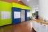 Modern apartment mailroom featuring vibrant green and blue walls, secure mailboxes, and a convenient coffee station.