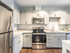 White-on-white kitchen with stainless steel appliances in a model apartment at The Chandler Bedford, NH apartments.