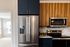 The James Apartments | Stainless Steel Modern kitchen with stainless steel appliances, including a double-door refrigerator and microwave, accented by dark blue and wooden cabinetry | Luxury Apartments in Haverhill MA