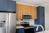 The James Apartments | Modern kitchen with stainless steel appliances, dark blue cabinets, and wooden upper cabinetry, featuring a sleek design with a double-door refrigerator and microwave | Luxury Apartments in Haverhill MA