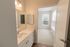 The James Apartments | View from a bathroom through a door into a well-lit bedroom with large windows and beige carpet | Luxury Apartments in Haverhill MA
