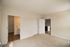 The James Apartments | Bedroom with beige carpet, multiple windows, and a door leading to a hallway with wooden flooring | Luxury Apartments in Haverhill MA