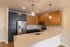 The James Apartments | Modern kitchen with stainless steel refrigerator, wood-paneled cabinets, and pendant lighting over a quartz countertop | Luxury Apartments in Haverhill MA