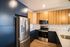The James Apartments | Spacious kitchen with a stainless steel refrigerator, microwave, and oven, complemented by wooden cabinetry and a quartz countertop | Luxury Apartments in Haverhill MA