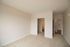 The James Apartments | Empty bedroom with carpeted floor, white walls, and a doorway leading to a walk in closet and then bathroom  | Luxury Apartments in Haverhill MA