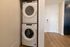 The James Apartments | Stacked white washer and dryer units in a compact laundry closet with wood-style flooring | Luxury Apartments in Haverhill MA