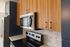 The James Apartments | Close-up of a modern kitchen featuring wooden upper cabinets, navy lower cabinets, stainless steel appliances, and white quartz countertops | Luxury Apartments in Haverhill MA