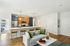 The James Apartments | Open-concept living room with a modern kitchen in the background, featuring a large island with bar seating, stainless steel appliances, and contemporary lighting fixtures | Luxury Apartments Haverhill MA