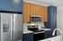 The James Apartments | Close-up view of a modern kitchen with stainless steel refrigerator, oven, microwave, wooden cabinets, and blue lower cabinets, accented with a bowl of lemons on the countertop | Luxury Apartments Haverhill MA