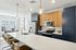 The James Apartments | Modern kitchen with a large island, pendant lighting, and bar stools, with a view of a dining area featuring large windows and a contemporary table | Luxury Apartments Haverhill MA