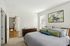 The James Apartments | Spacious bedroom with neutral tones, featuring a large bed with decorative pillows, a wooden dresser, and abstract art above the headboard | Luxury Apartments Haverhill MA