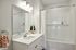 The James Apartments | Bright and clean bathroom with a white vanity, large mirror, and a bathtub with a white tiled shower and curtain. | Luxury Apartments Haverhill MA