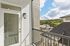 The James Apartments | Private balcony with a glass door and exterior light fixture, overlooking a parking lot and scenic tree-lined hills in the background. | Luxury Apartments Haverhill MA