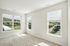 The James Apartments | Bright, unfurnished room with beige carpet and multiple windows offering a view of green hills and outdoor facilities. | Luxury Apartments Haverhill MA