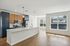 The James Apartments | Modern open-concept kitchen with an island and pendant lights, featuring stainless steel appliances and a large, unfurnished living area with hardwood floors. | Luxury Apartments Haverhill MA