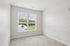 The James Apartments | Unfurnished bedroom with beige carpeting, featuring a large window that offers a view of a green outdoor area and hills. | Luxury Apartments Haverhill MA